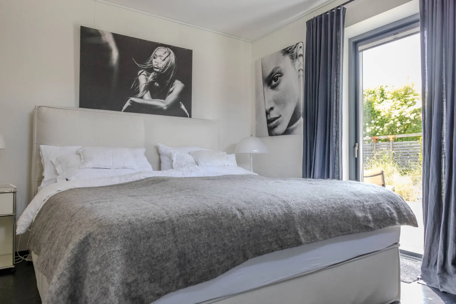 Doppelbett mit grauer Decke, Fotokunst und Terrassentür mit grauem Vorhang