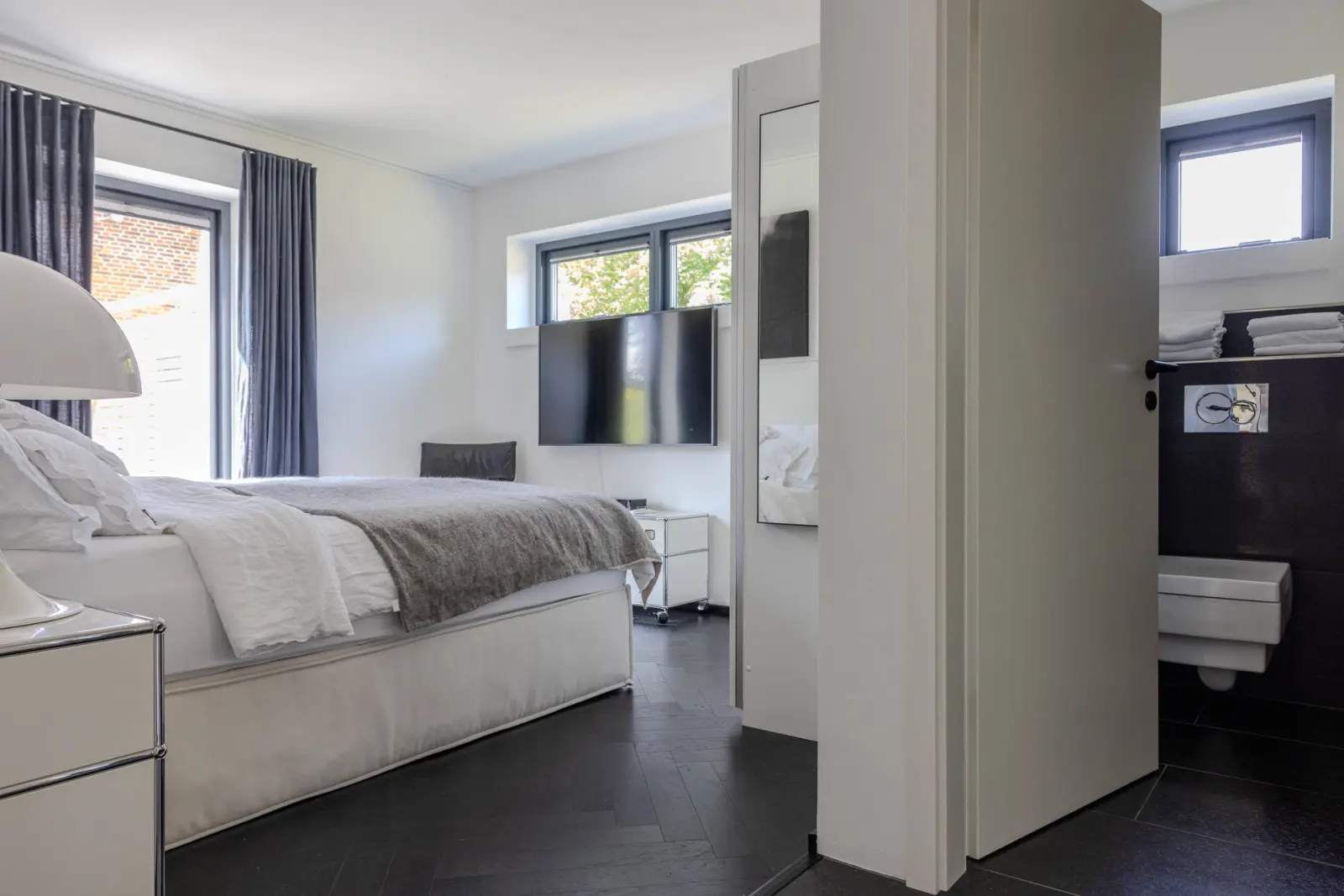 Schlafzimmer mit Wand-TV und Durchgang zum Bad