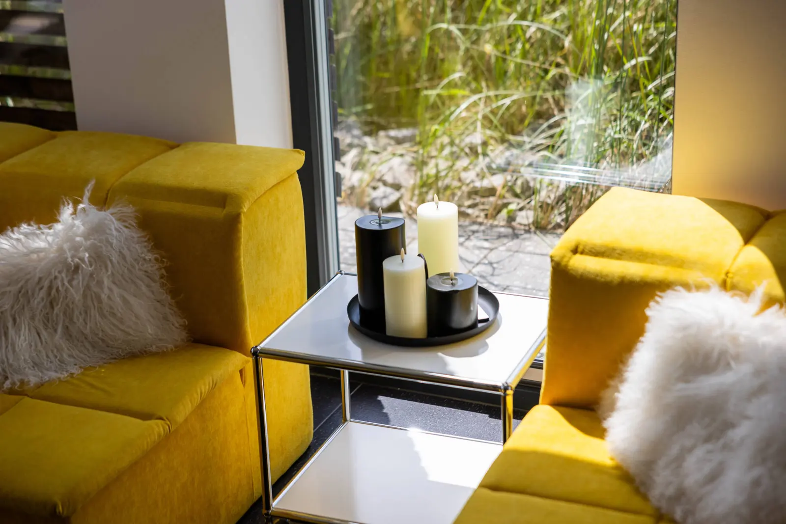 Gelbe Sofaecke mit Fellkissen und weißem Beistelltisch mit Kerzen