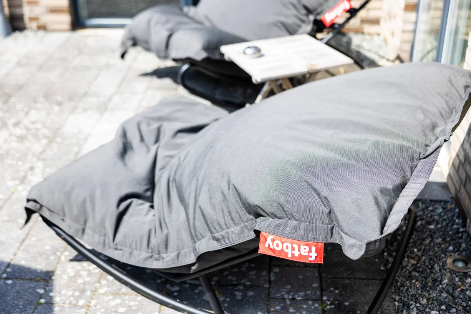 Grauer Sitzsack-Sessel mit Logo auf der Terrasse, Detailaufnahme