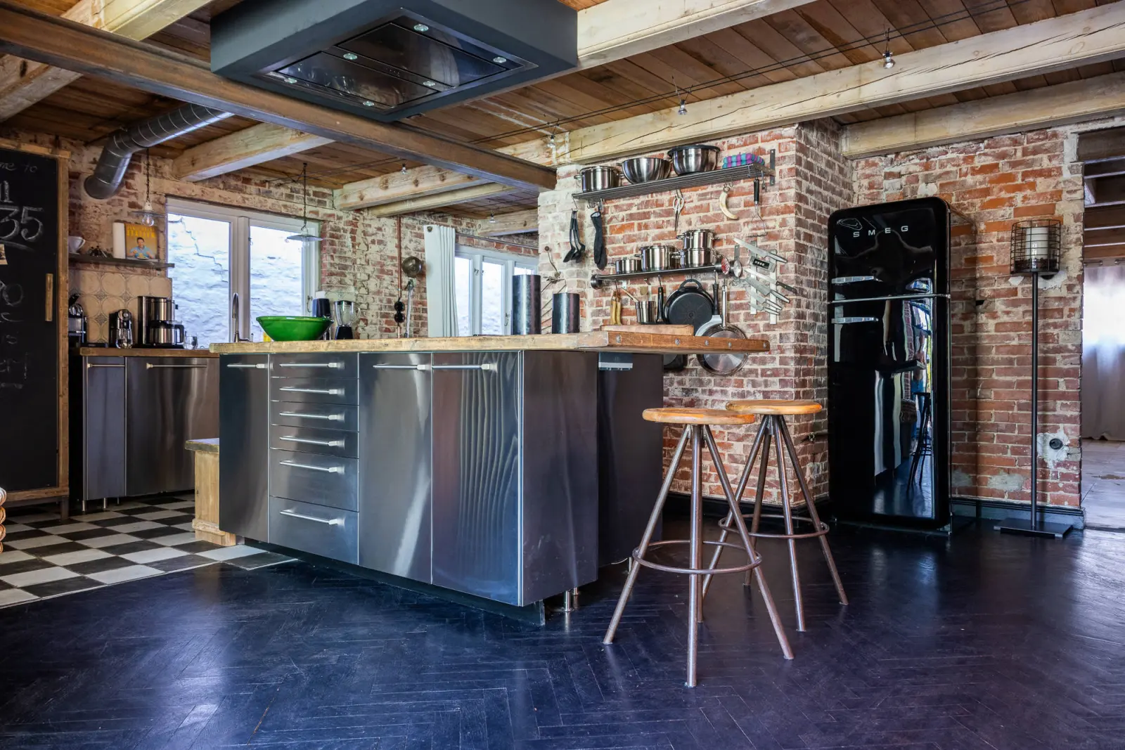 Küche mit Edelstahlinsel, Barhockern, schwarzem Retro-Kühlschrank und Schachbrettboden