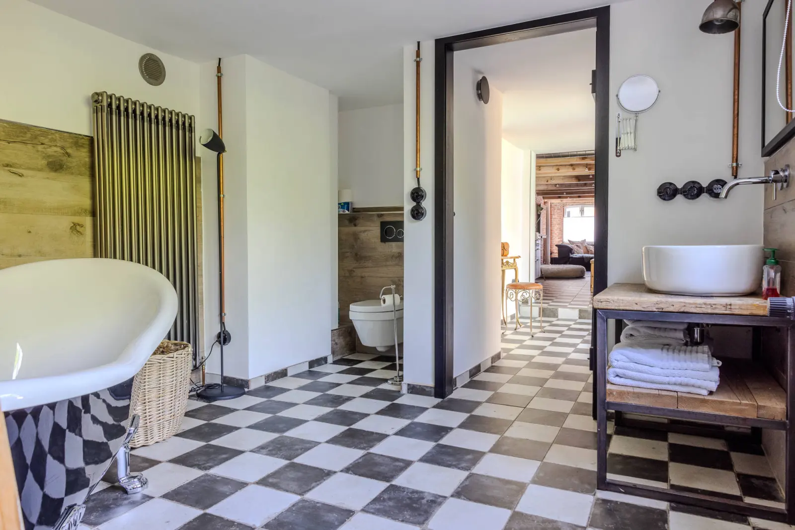 Badezimmer mit Wanne, Heizkörper, Aufsatzwaschbecken und Schachbrettfliesen