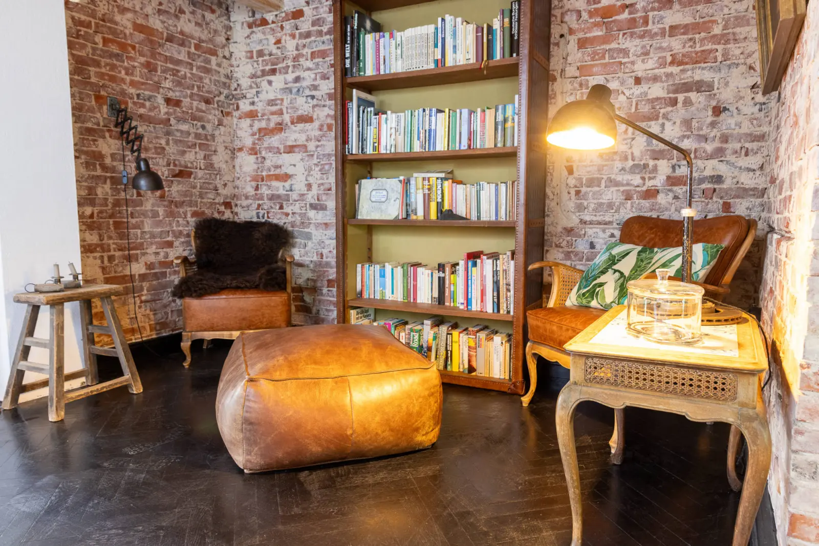 Leseecke mit Bücherregal, Ledersessel, Lederpouf und Backsteinwand
