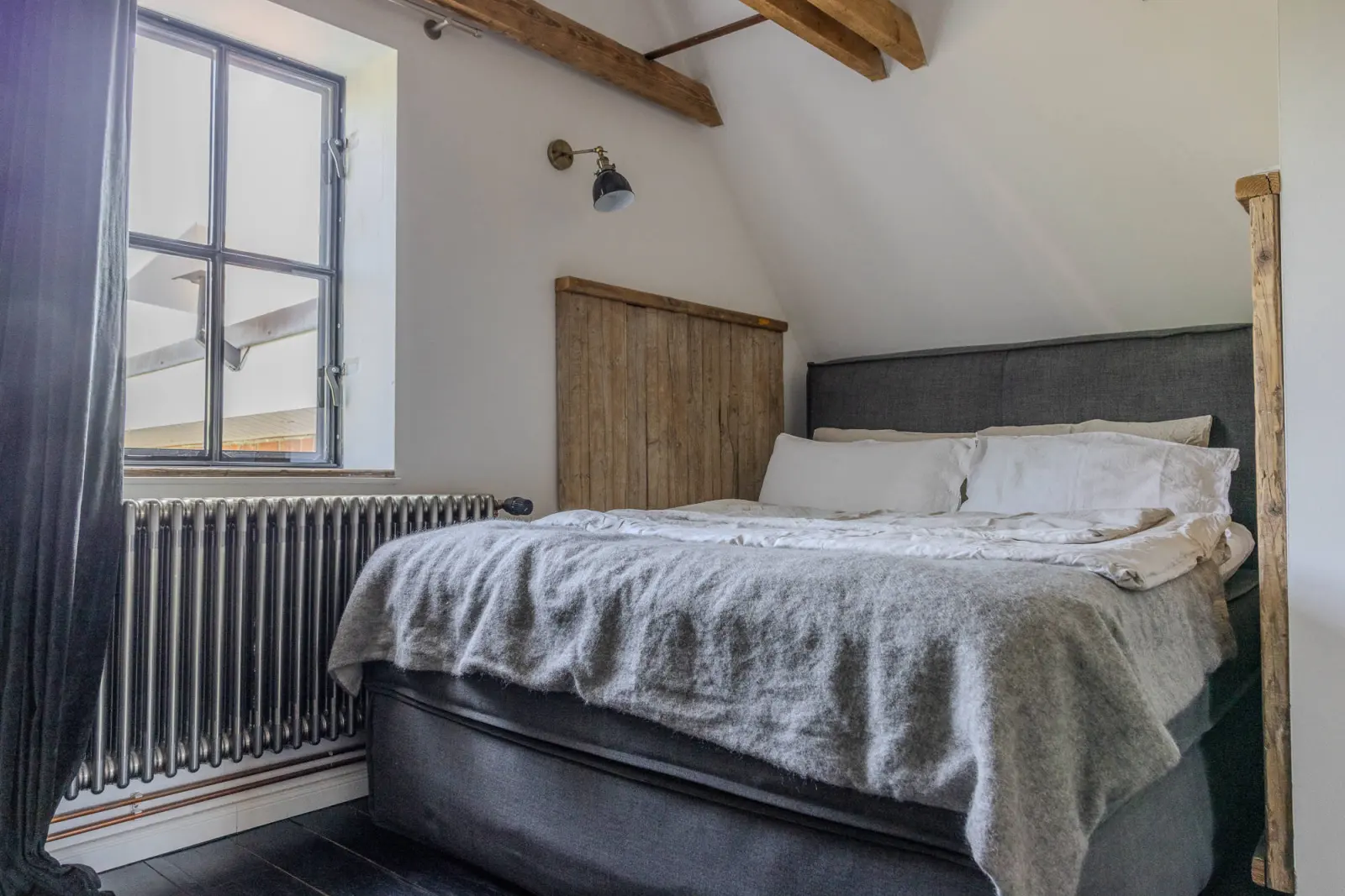 Schlafzimmer unterm Dach mit Boxspringbett, Heizkörper und Sprossenfenster