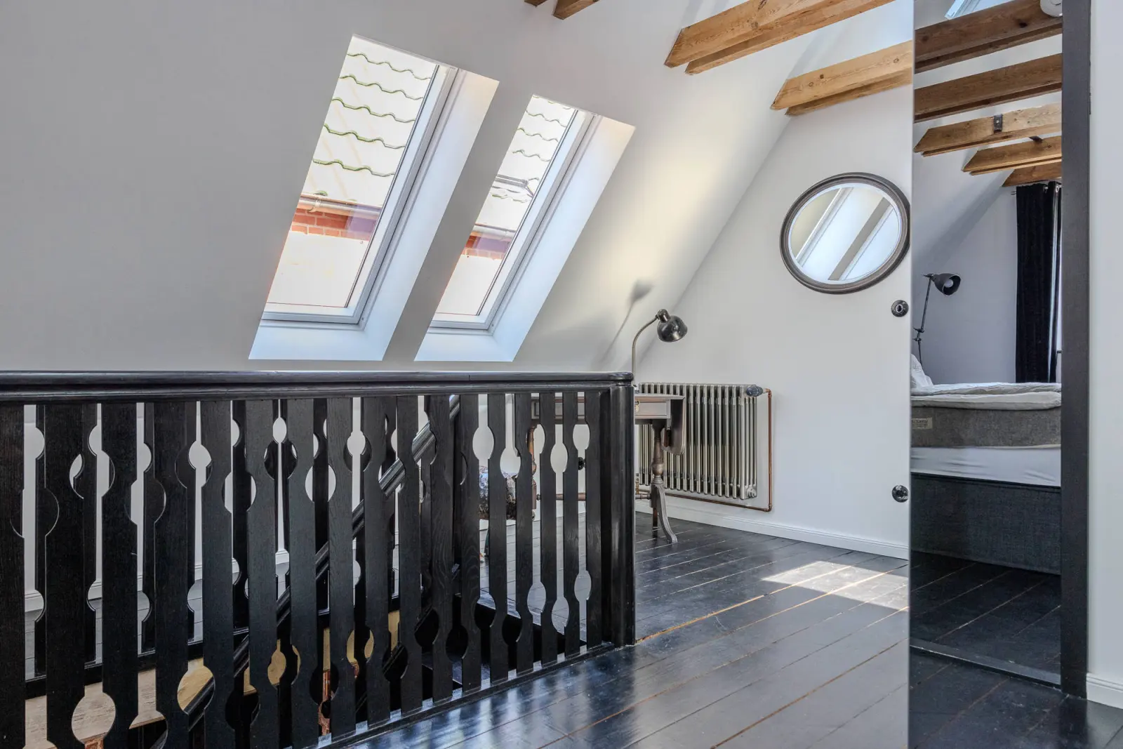 Galerie mit schwarzem Geländer, Dachfenstern und Blick ins Schlafzimmer