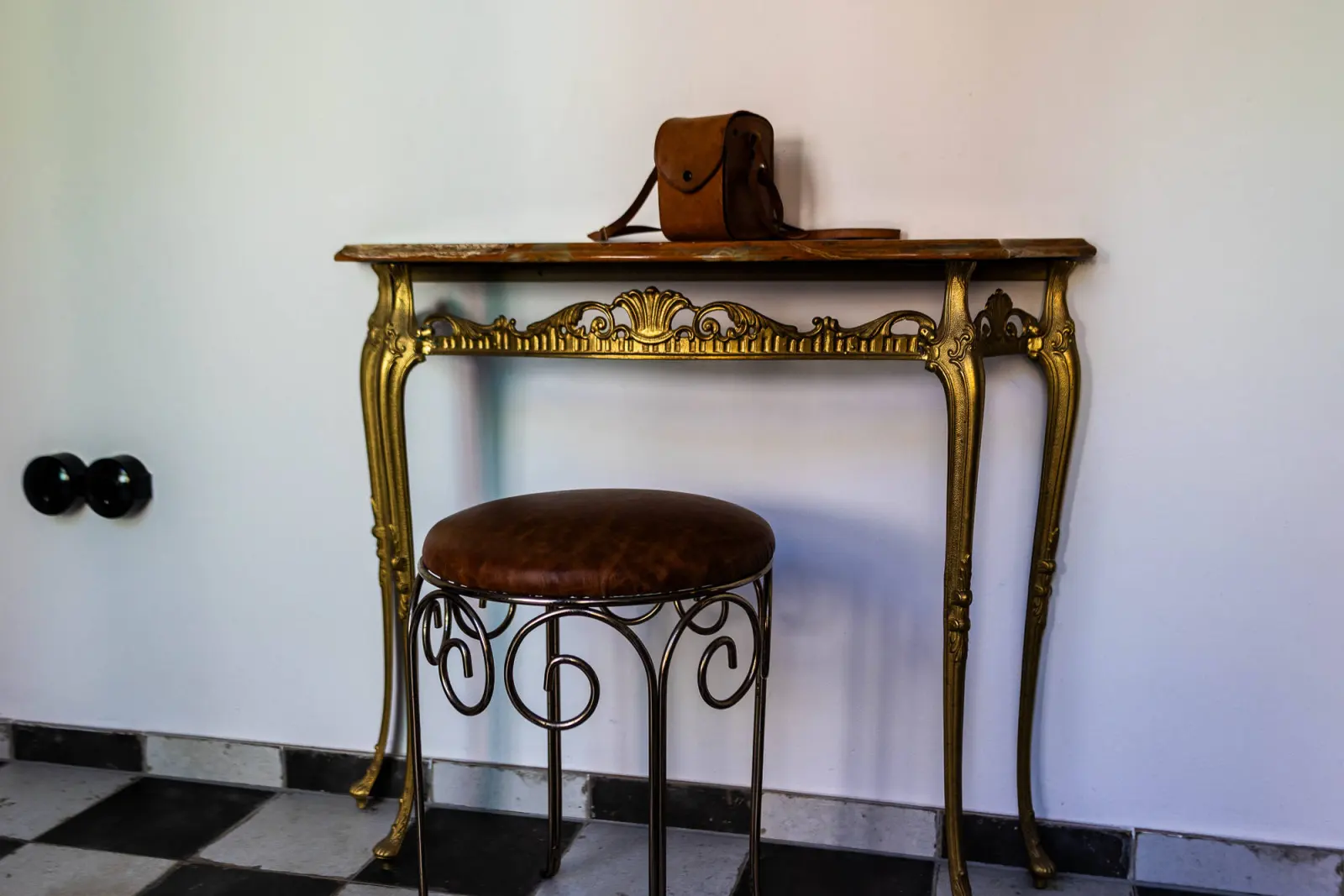 Goldene Konsole mit Polsterhocker und Ledertasche im Flur