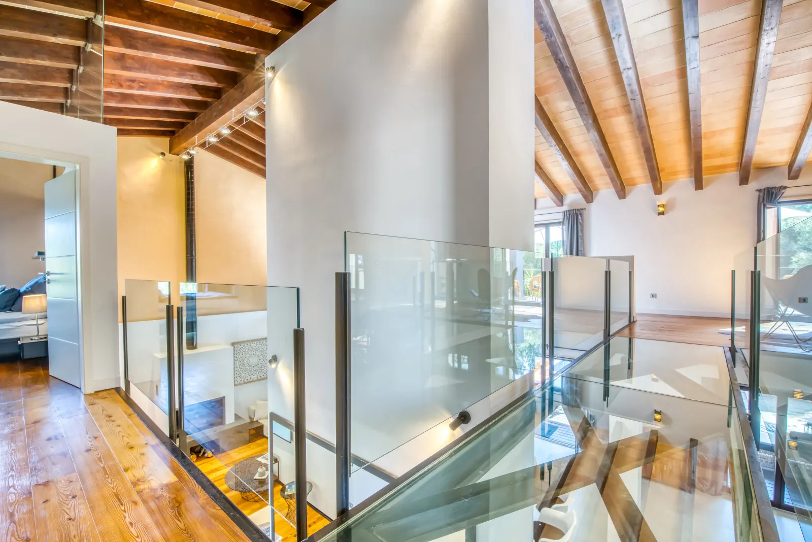 Galerie mit Glasgeländer und Holzbalkendecke über dem Wohnraum