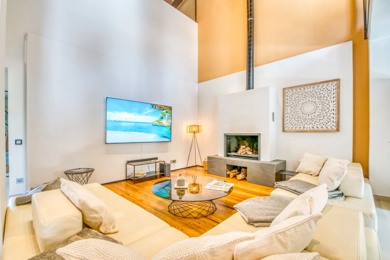 Wohnzimmer mit weißer Sofalandschaft, offenem Kamin und Wand-TV