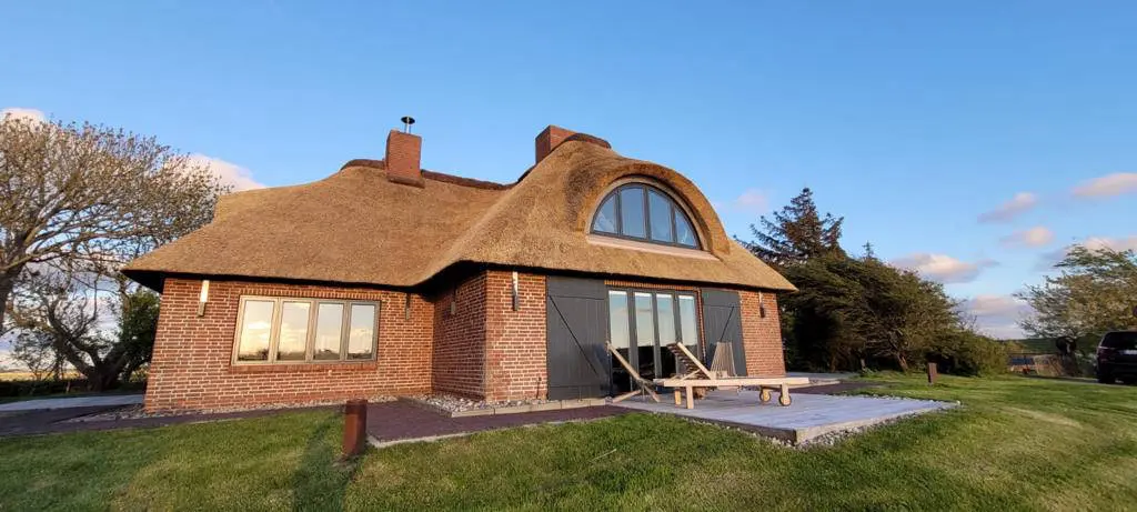 Reetdachhaus mit Sonnenliegen und Terrasse, Rückseite im Abendlicht