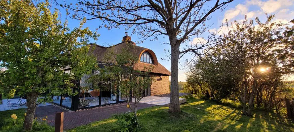 Landhaus im Garten mit Obstbäumen und tief stehender Abendsonne