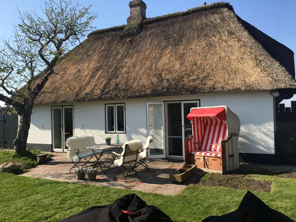 Reetdachhaus mit Terrasse, Strandkorb und Sitzgruppe im Sommer