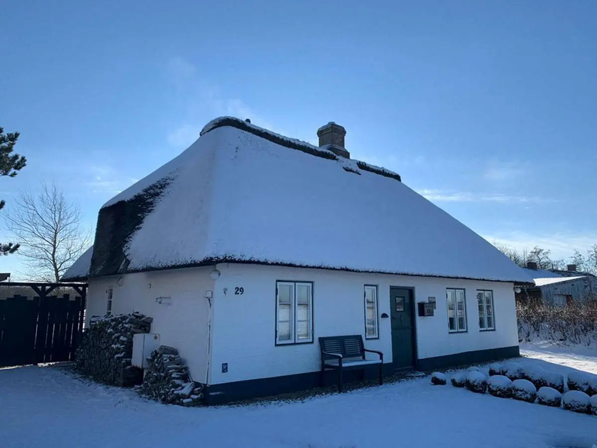 Reetdachhaus im Schnee unter klarem Winterhimmel