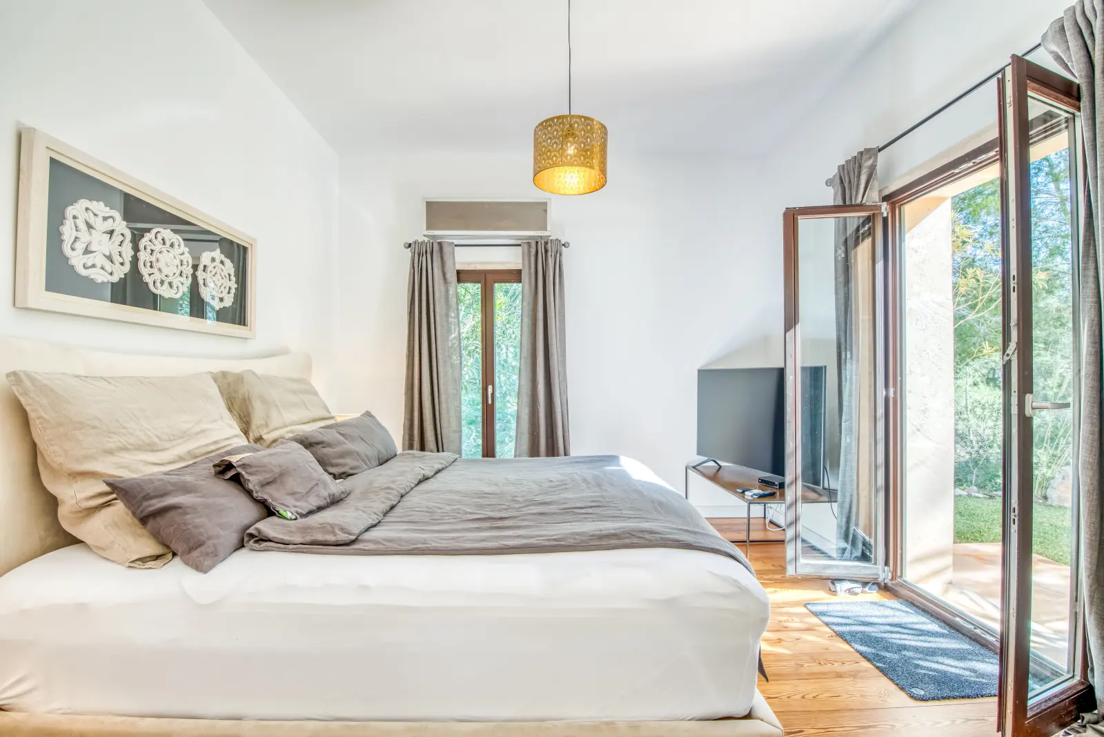 Schlafzimmer mit dunklem Boxspringbett, Fotokunst und Sessel mit Fellauflage