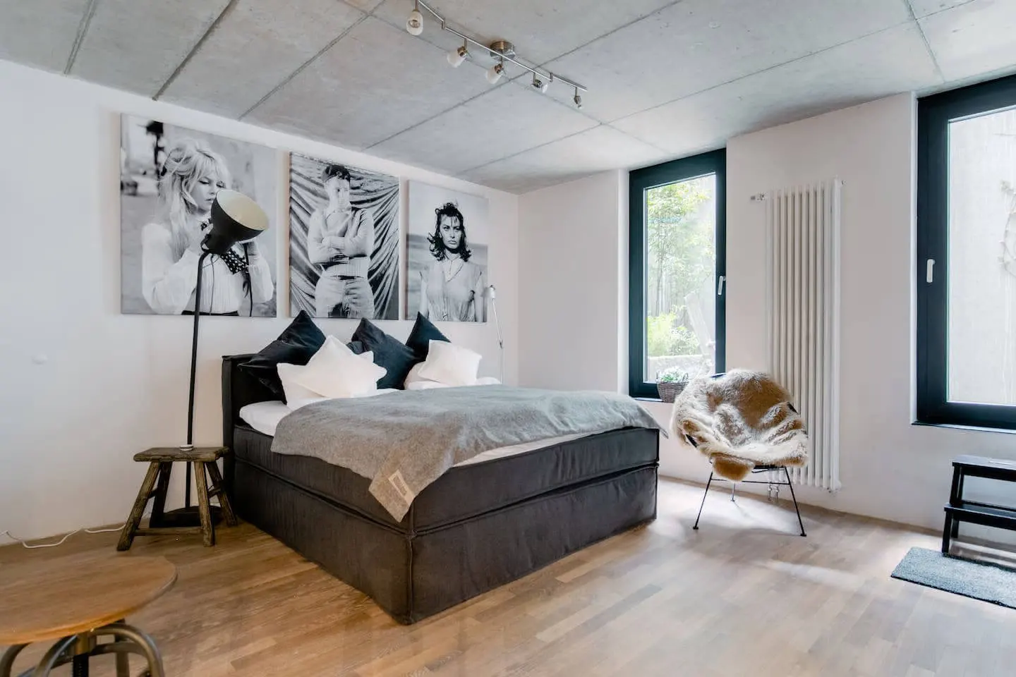Schlafzimmer mit dunklem Boxspringbett, Porträtbildern und Wandleuchte