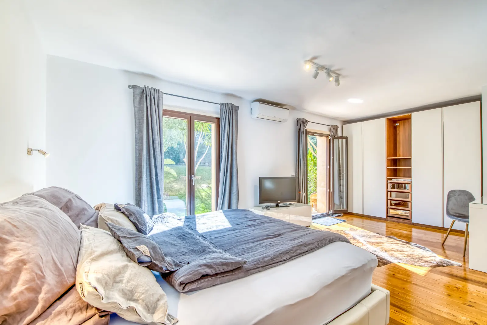 Großes Schlafzimmer mit Parkett, Einbauschrank, Fernseher und Terrassentür