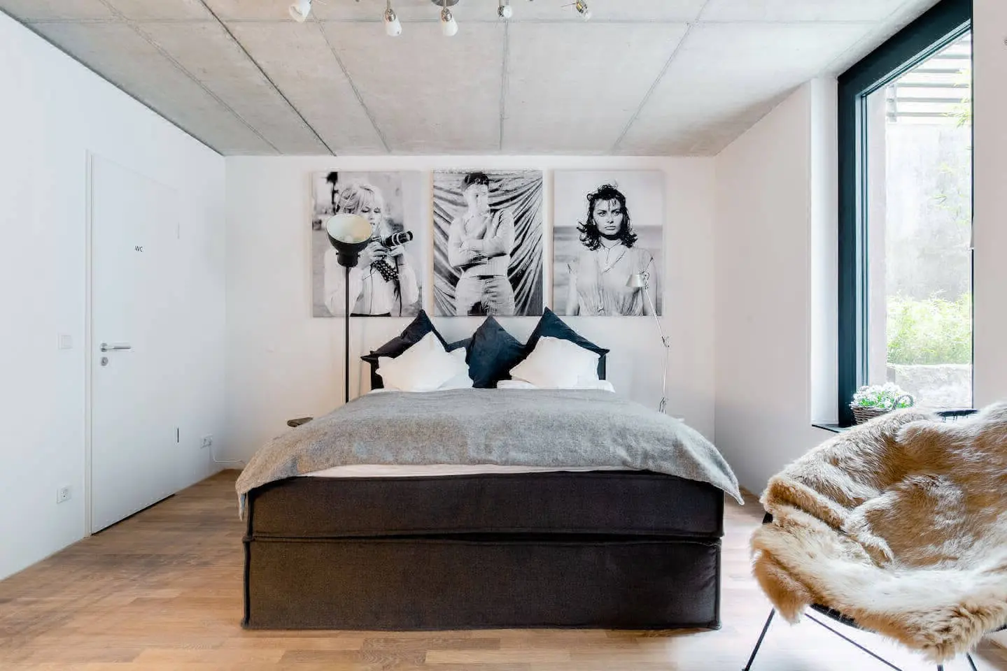 Schlafzimmer mit Boxspringbett, Fellsessel und Fotokunst an der Wand
