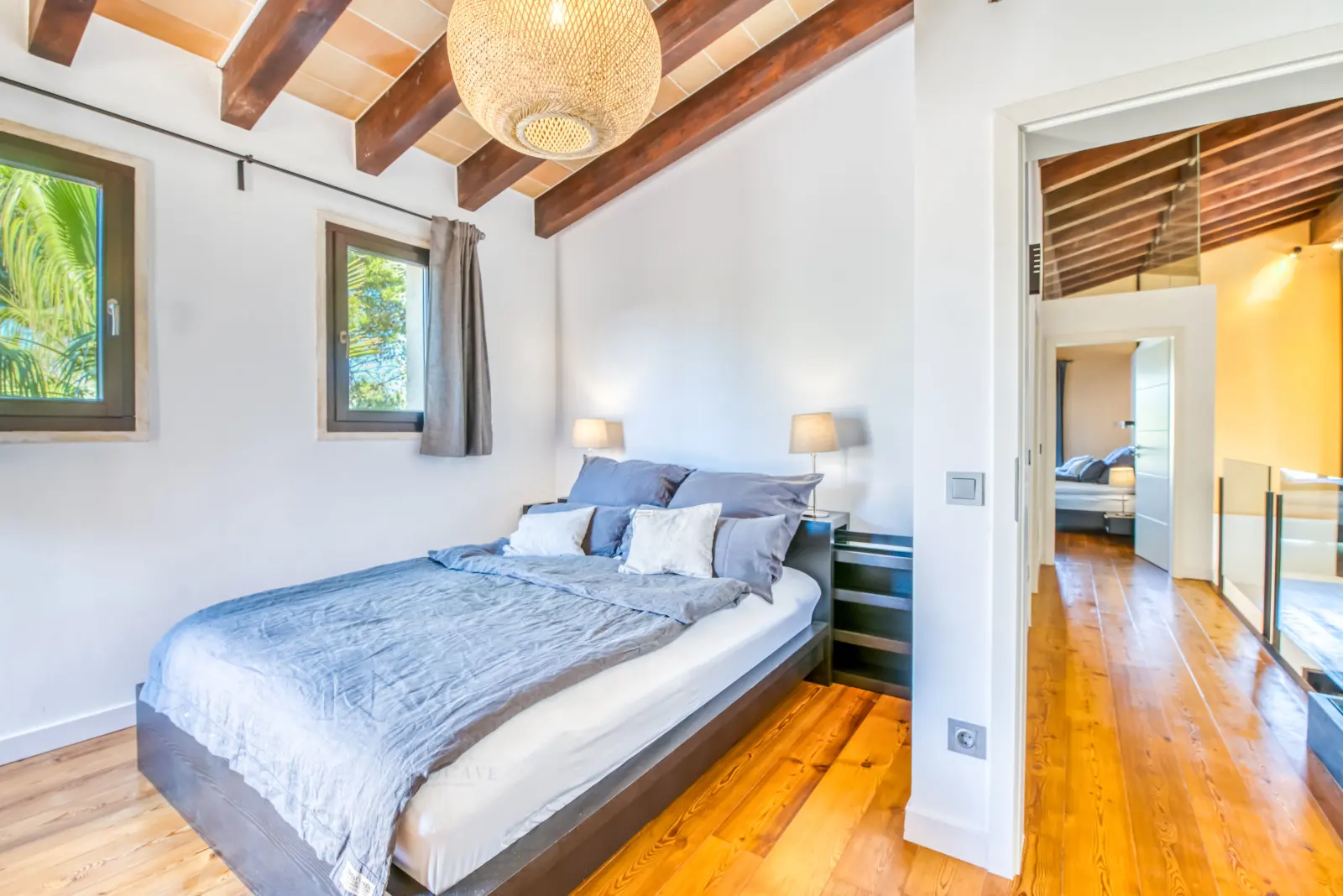 Schlafzimmer mit Holzbalkendecke, Rattan-Pendelleuchte und Doppelbett