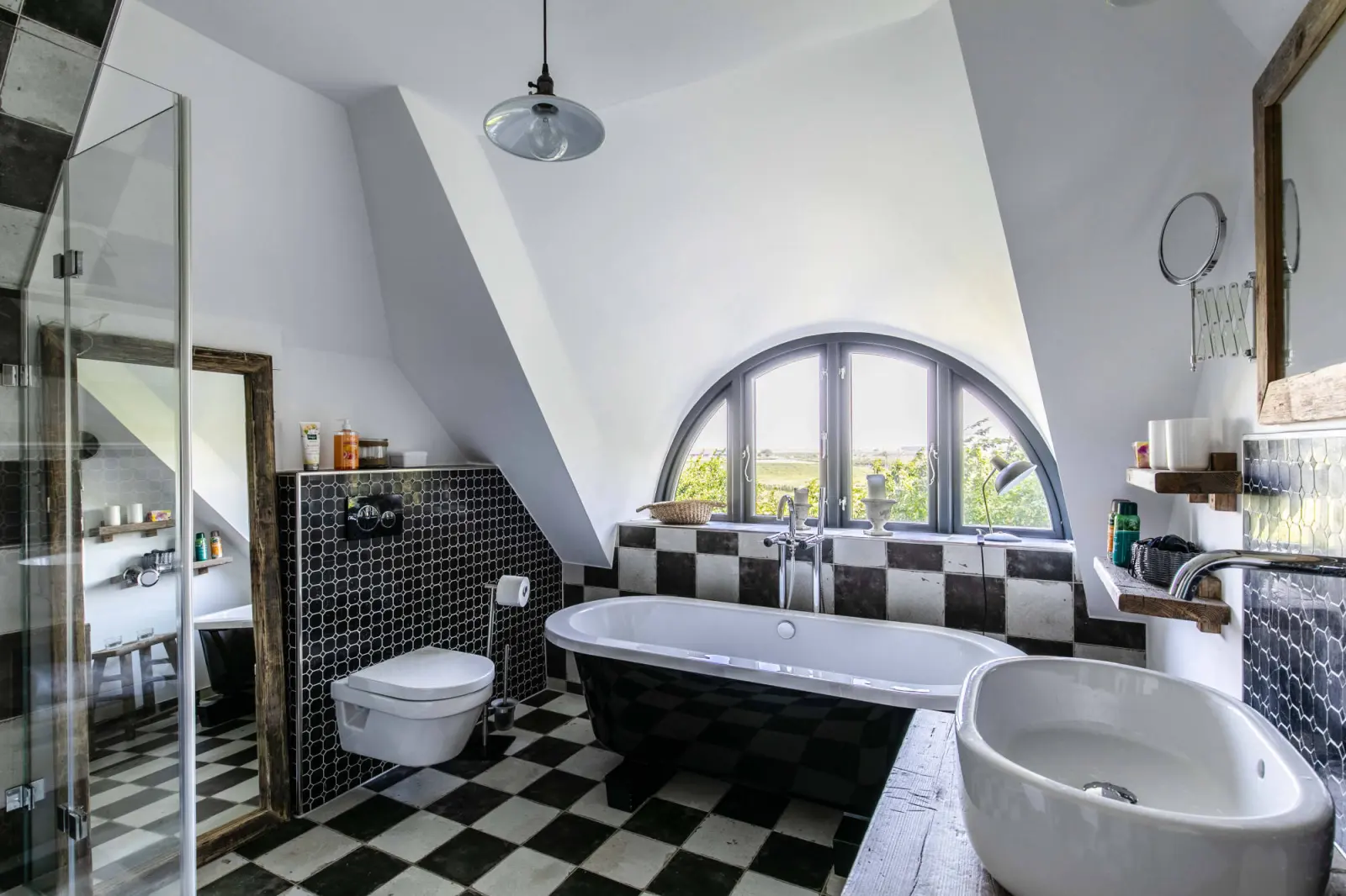Badezimmer unterm Dach mit Wanne, Wand-WC, Waschschale und Schachbrettboden