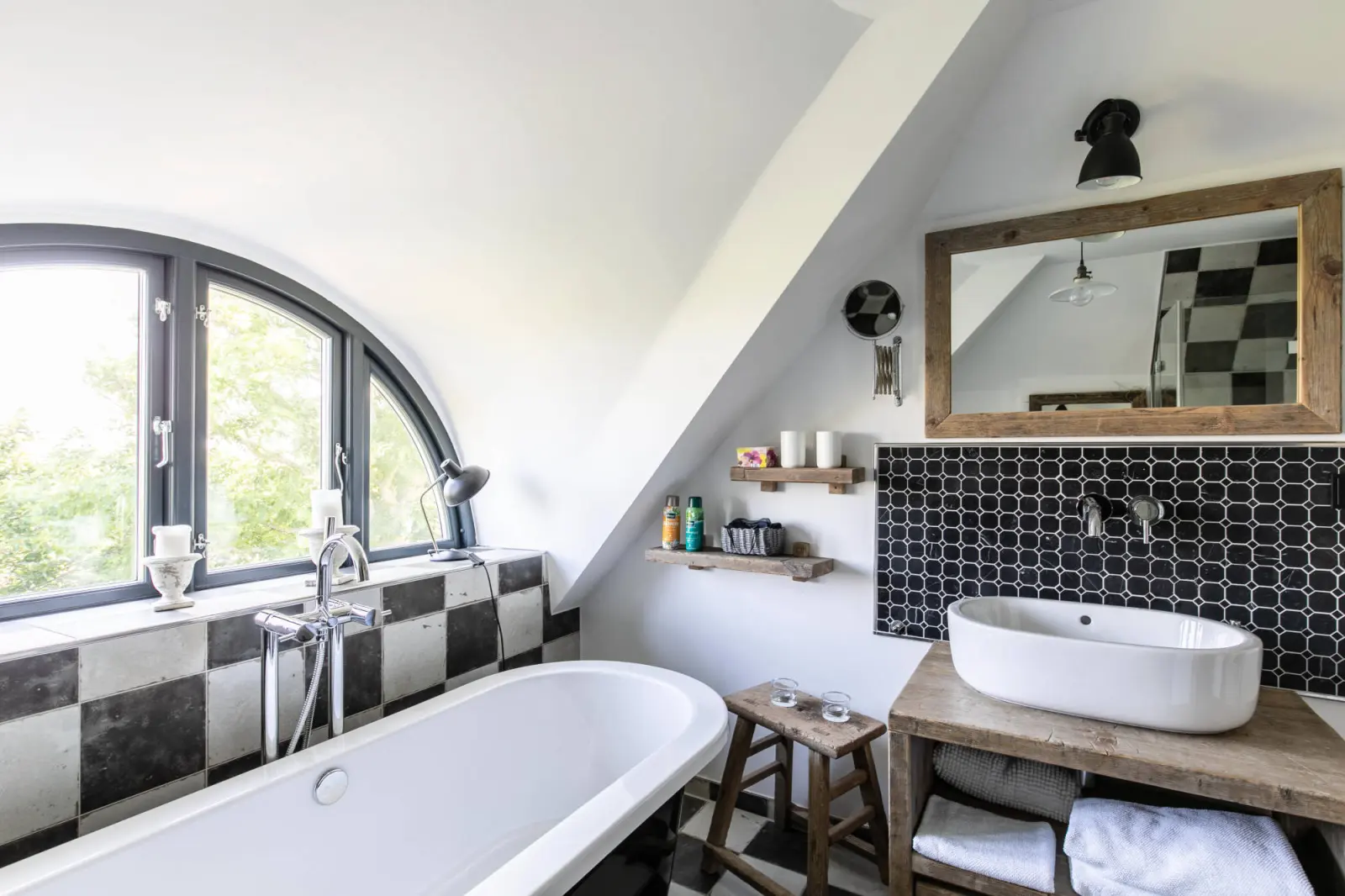 Freistehende Wanne und Waschtisch mit Holzspiegel im Bad mit Halbrundfenster
