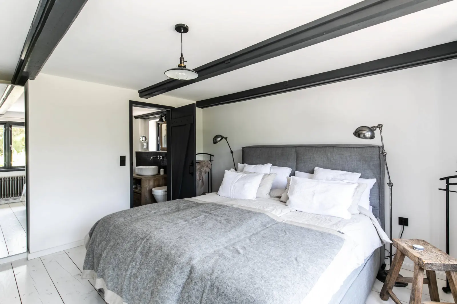 Schlafzimmer mit Doppelbett, grauer Decke und schwarzen Deckenbalken
