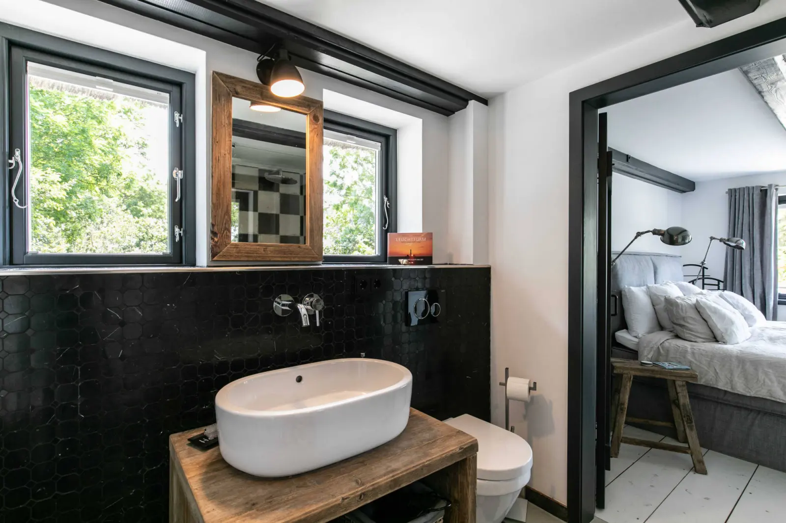 Waschtisch mit ovalem Becken und Holzrahmenspiegel, Blick ins Schlafzimmer
