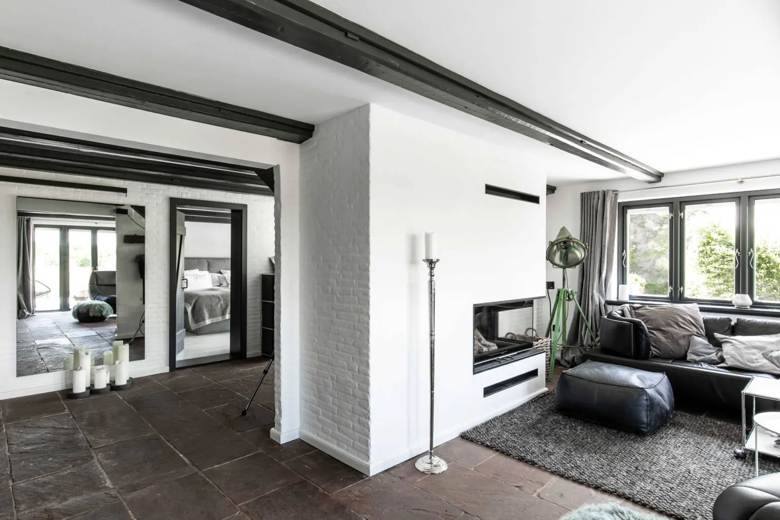 Wohnbereich mit Sofa und Pouf, Durchblick zum Flur mit Spiegeln