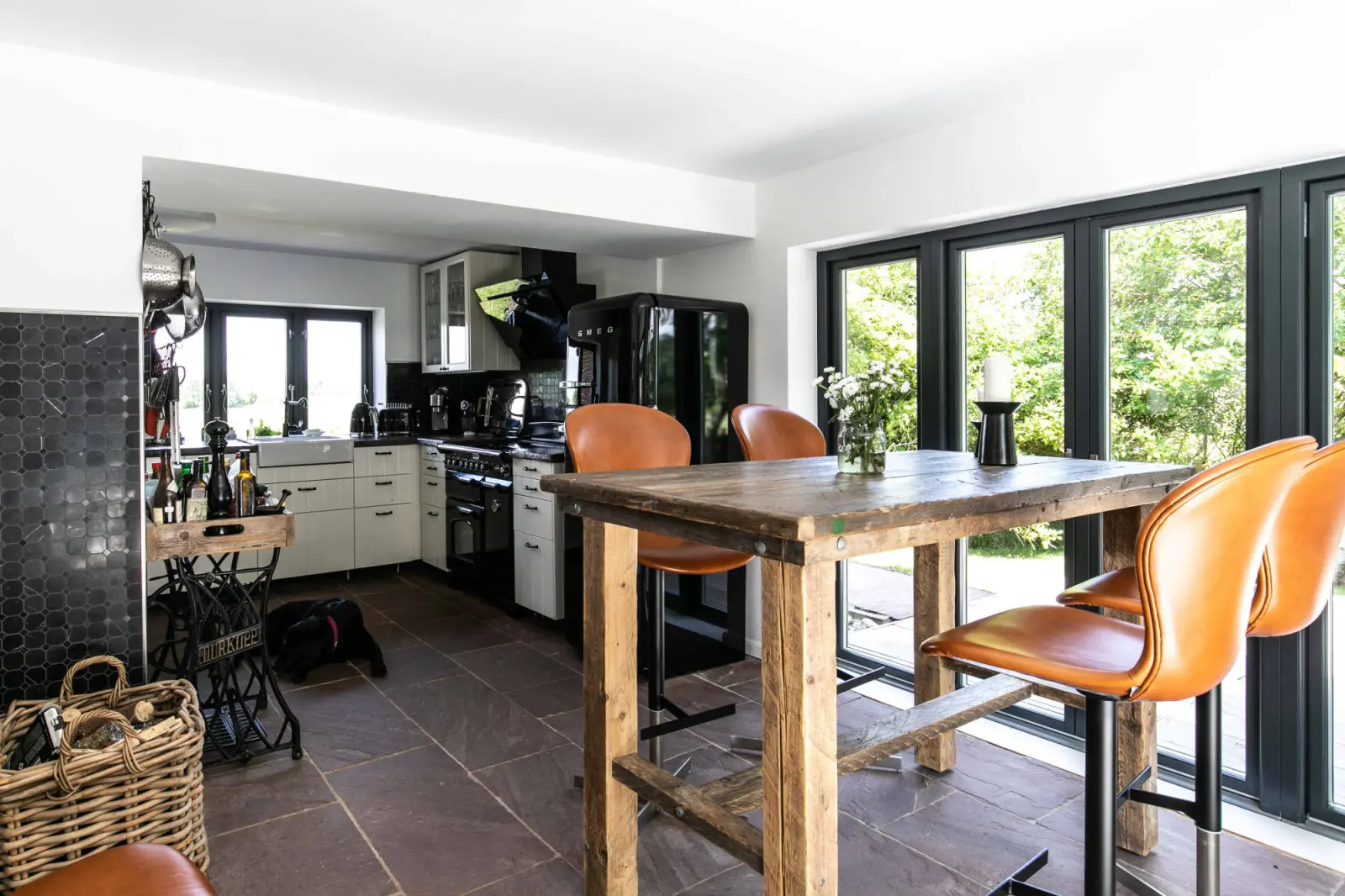 Offene Küche mit Holztisch, Lederstühlen und Fensterfront zum Garten