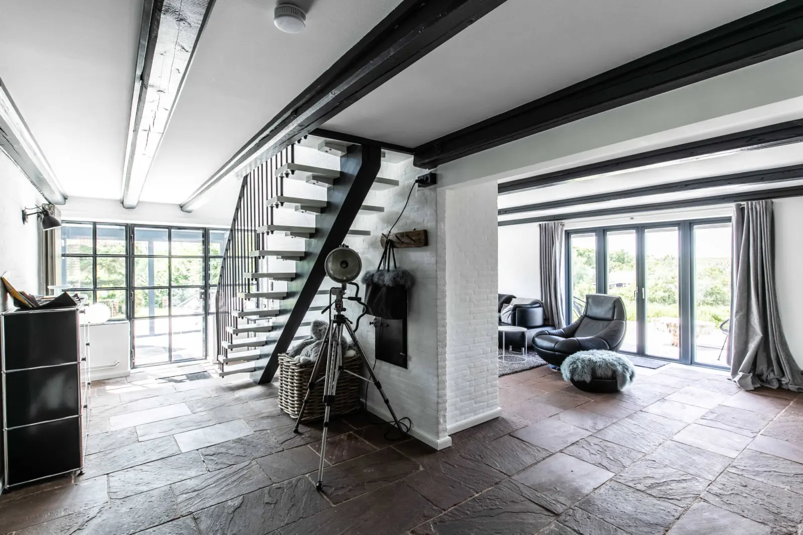 Offener Wohnraum mit Treppe, Deckenbalken und großer Fensterfront