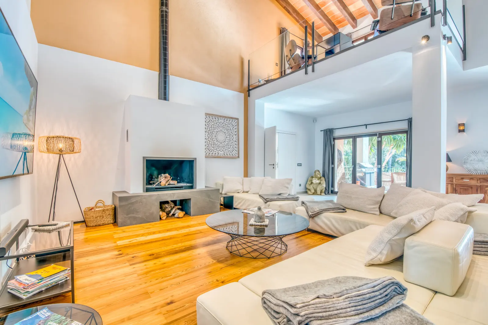 Weitläufiger Wohnraum mit weißen Sofas, Galerie und Fenstertüren zum Garten